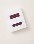 A white rectangular gift box with two horizontal cutouts showing a red floral patterned fabric, wrapped with a white paper band labeled 'solly baby' on a light beige background.