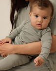 Baby sitting on a woman's lap wearing matching mist pointelle sleep sets