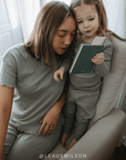 Woman and child sitting together on a chair, looking at a book.