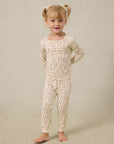 Toddler girl wearing cream-colored long-sleeve top and leggings with small brown floral print pajamas.