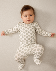 Baby wearing a patterned onesie lying on a neutral background