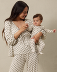 Woman and baby wearing matching patterned outfits against a neutral background