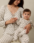 Woman and baby in matching patterned outfits sitting together.