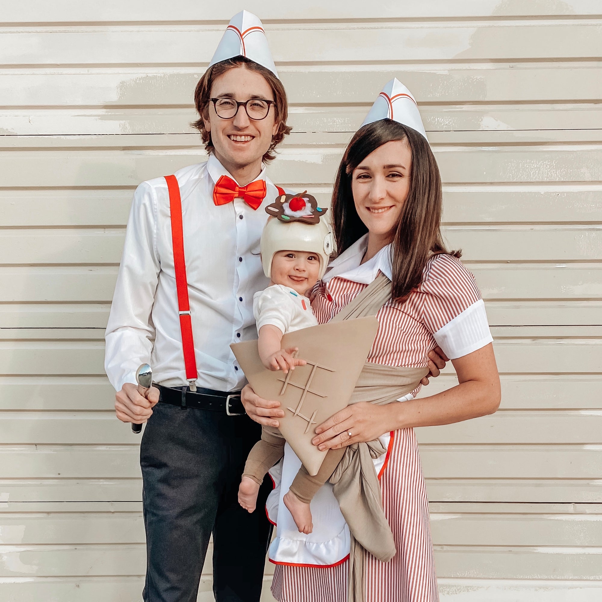 Family wearing retro diner costumes with white paper hats, red bow tie and suspenders, and baby in ice cream cone outfit.