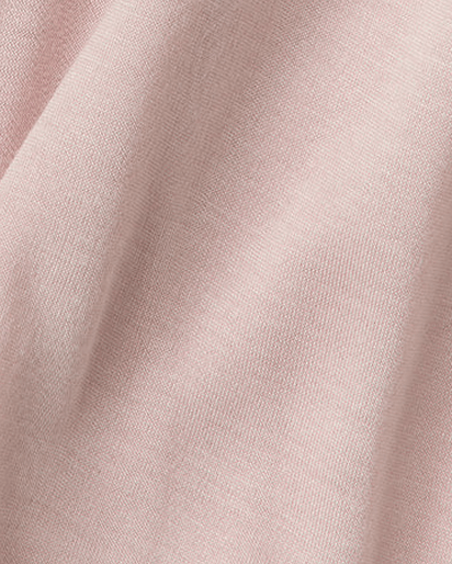 A close-up of soft blush pink fabric with a fine knit texture and gentle folds.