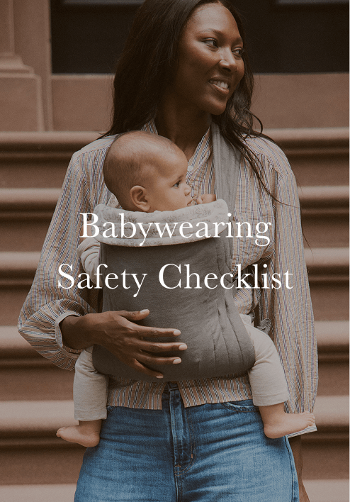Woman wearing a striped shirt and jeans carrying a baby in a gray baby carrier on her front.