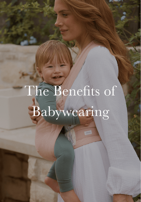 Woman wearing a white dress carrying a smiling baby in a pink fabric baby carrier outdoors with text overlay.