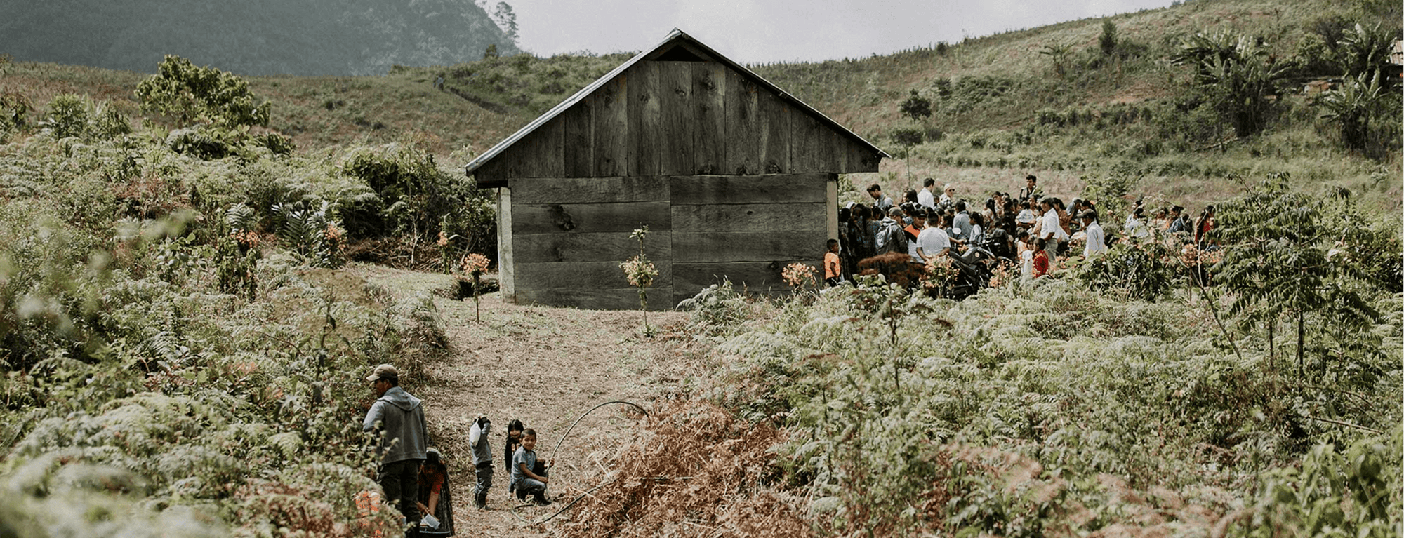 Wooden structure in a rural setting with people gathered around