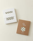 Two packages of green and white checkered cloth, one in white box and one in brown box labeled "The Solly Dolly