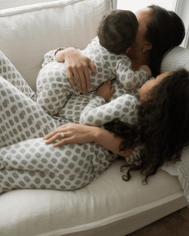 Woman and child in matching pajamas hugging on a couch