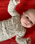 Baby wearing a strawberry pajama set on a red blanket @bexbeckman