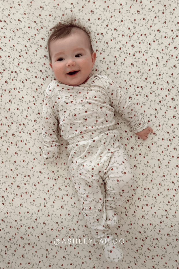Baby lying on a strawberry patterned surface wearing a matching outfit. @ashleylapido