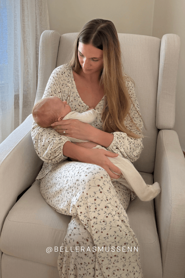 Woman in a strawberry outfit holding a baby in a beige armchair. @Bellerasmussenn