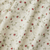 Fabric with a red strawberry and green vine pattern on a cream background
