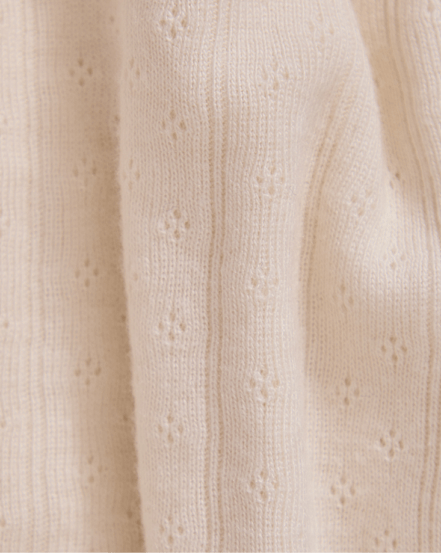 Close-up of cream fabric with a subtle pointelle pattern