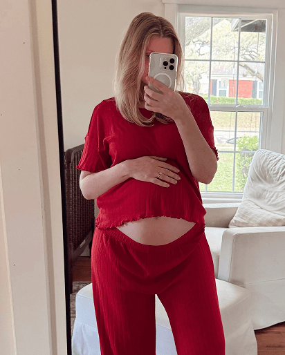 Woman wearing a loose red ribbed short-sleeve top and matching high-waisted pants in front of a window.