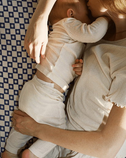Matching beige ribbed knit loungewear set for baby and adult with puff sleeve top and high-waisted pants on blue patterned blanket.