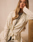 Woman wearing a strawberry patterned robe against a beige background