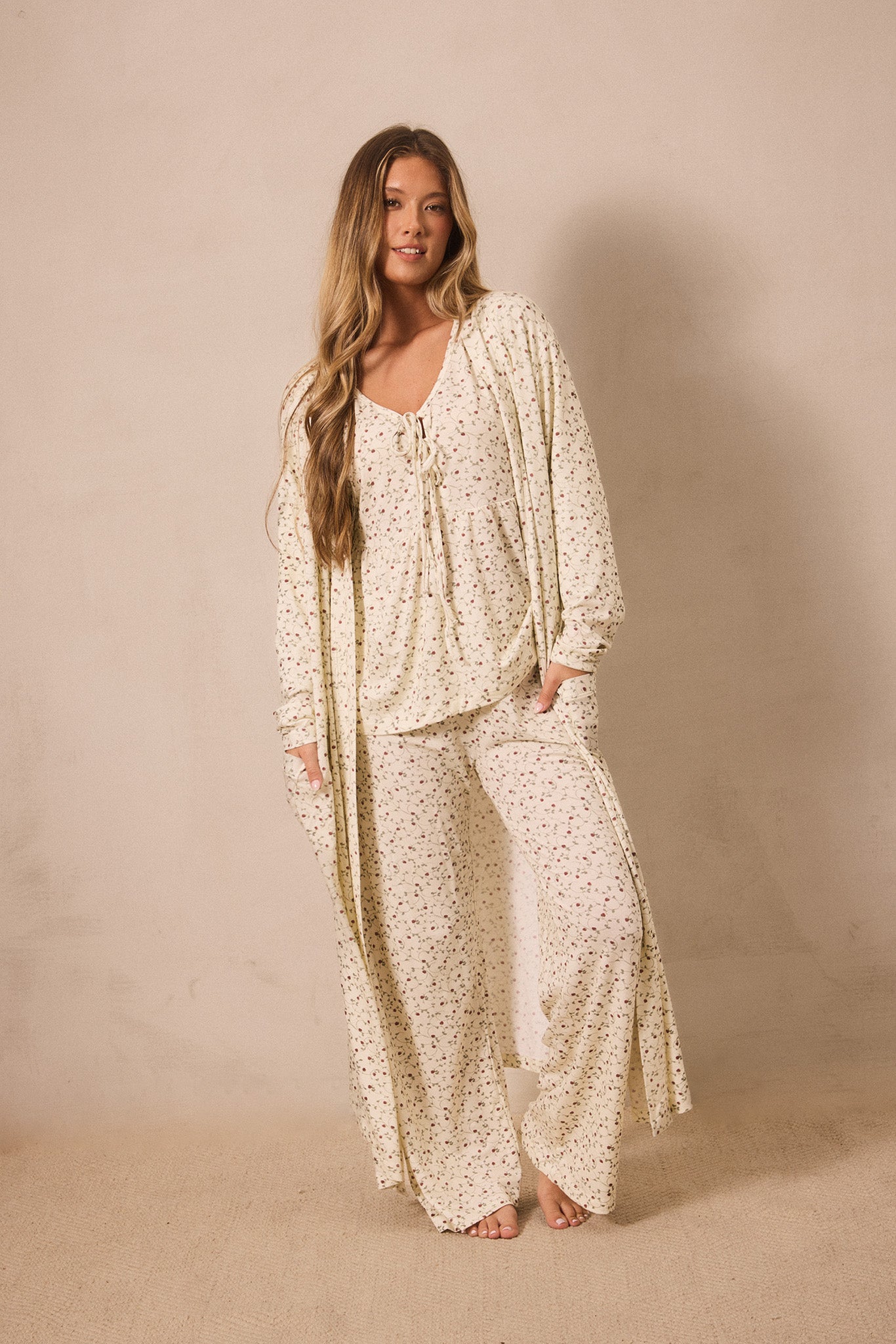 Woman wearing a matching strawberry robe and sleep set outfit against a beige background