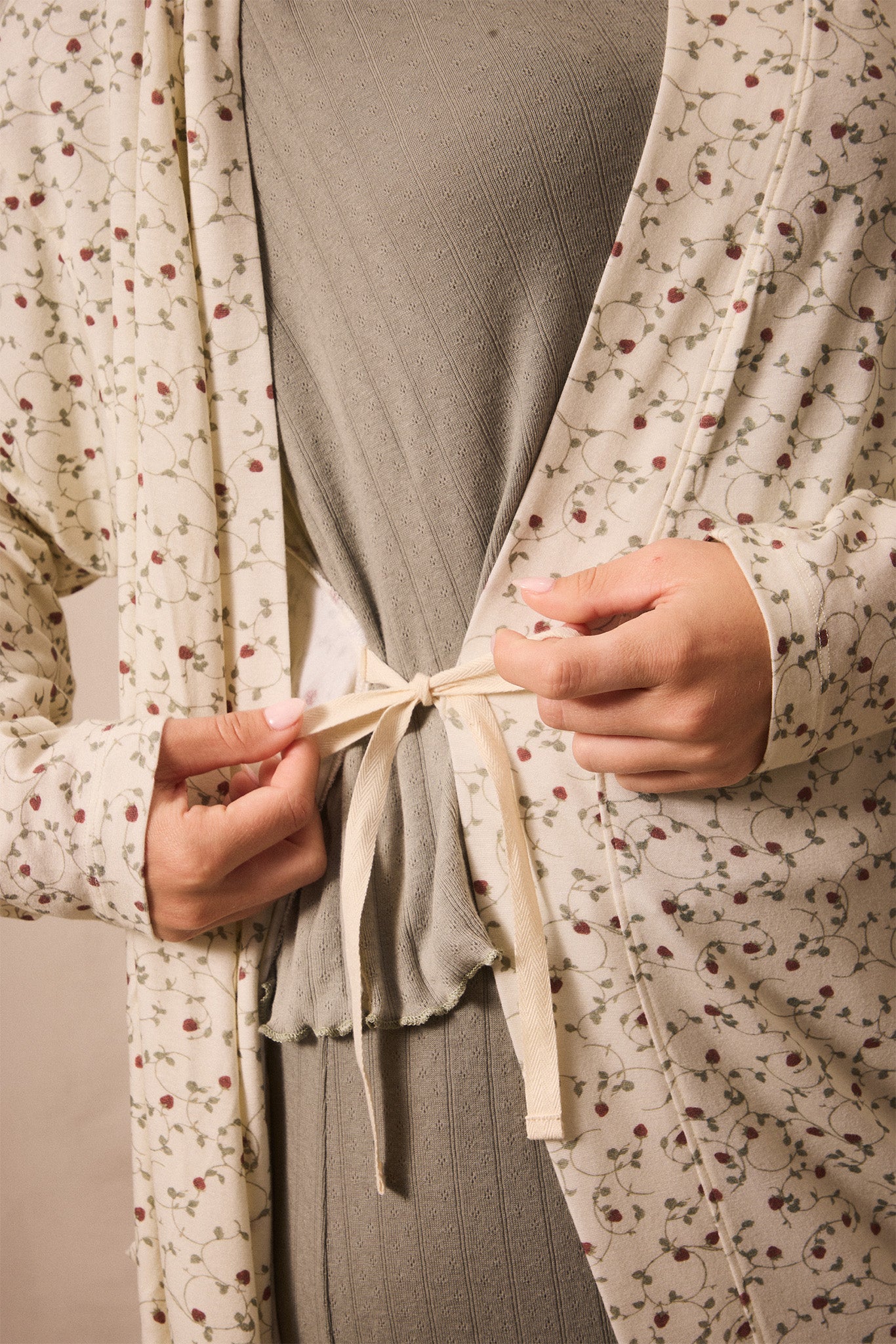 Person wearing a strawberry robe tying it around their waist.