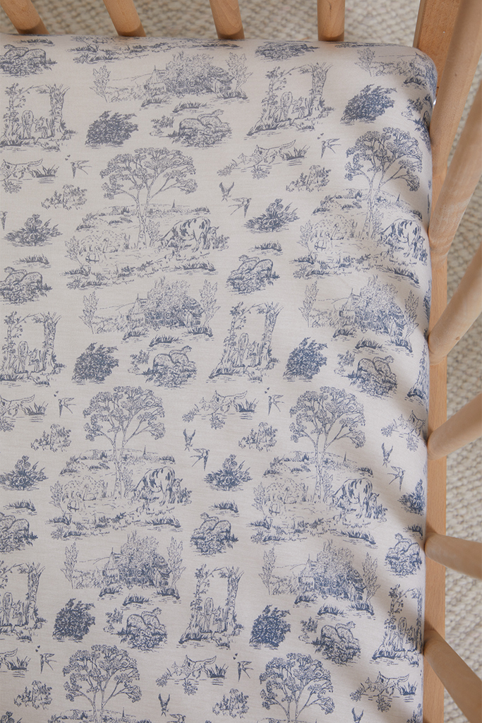 Beige chair cushion with detailed blue toile pattern featuring trees, animals, and countryside scenes.