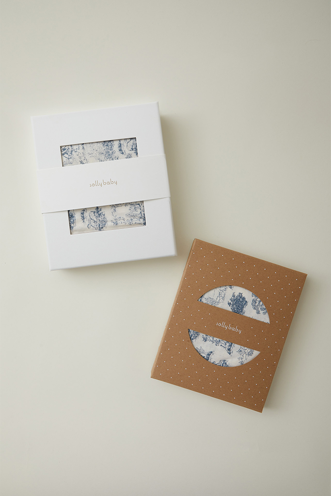 Two packaged fabric sets with blue toile print, one in white box and one in brown box with white polka dots, labeled "jollybaby".