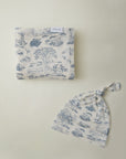 Cream-colored baby blanket and knotted hat set with blue nature and animal toile pattern