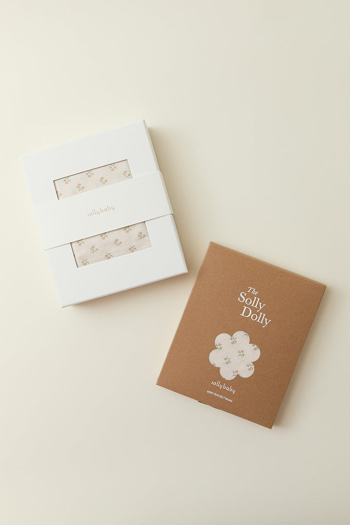 White and brown gift boxes with floral patterned fabric inside branded "sollybaby" and "The Solly Dolly" text on packaging.