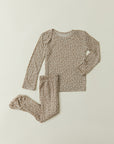 A flat lay of Solly Baby's two-piece baby pajamas in the Cream Floral Print, featuring petite cream buds gently scattered atop a soft taupe brown base. The pajamas feature footed bottoms and an easy wide-neck top and are available in sizes 0m-12m.