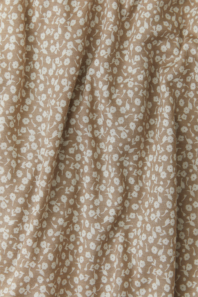 A close-up fabric shot of Solly Baby's Cream Floral print, featuring delicate cream flowers on top of a taupe background.  