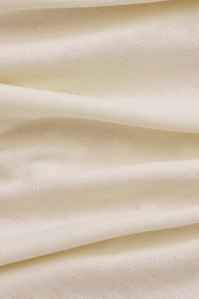 Close-up of cream pointelle fabric with a subtle pattern