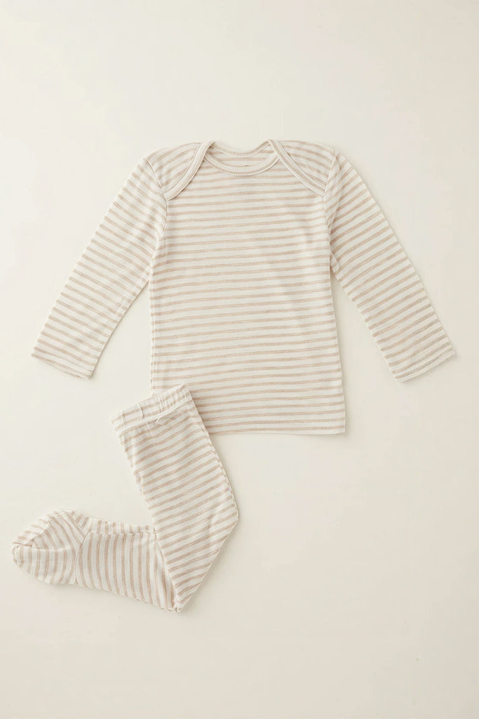 A two-piece baby pajama set featuring a long-sleeve top and matching footed pants, both with thin horizontal beige stripes on an off-white base, laid flat on a light cream background.