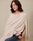 Beige and white striped nursing cover worn by woman sitting with baby feet visible underneath.