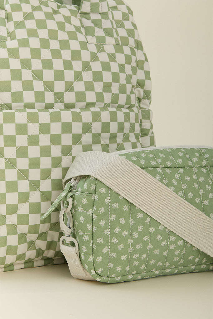 A close-up of the Solly Baby Fern Chequer Totepack diaper bag featuring a soft green and cream checkered print with small crossbody bag in a matching soft green and cream floral print. 