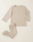 A two-piece baby pajama set in a heathered oatmeal beige color, featuring a long-sleeve top and matching footed pants, laid flat on a light cream background.