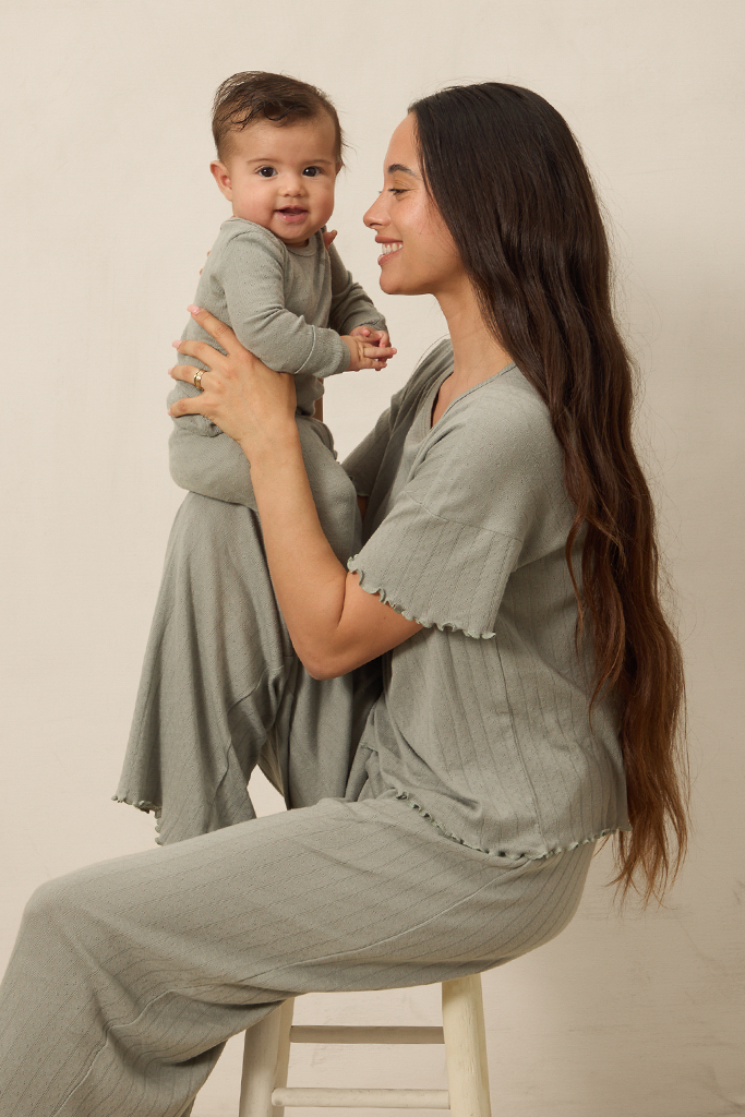 Woman in matching mist pointelle sleep sets holding a baby against a plain background