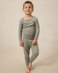 Young boy wearing a mist pointelle sleep set on a beige background