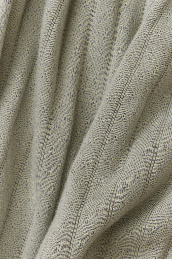 Close-up of textured light green fabric with visible pointelle pattern