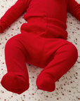 Red pointelle baby sleep set on a strawberry-patterned surface