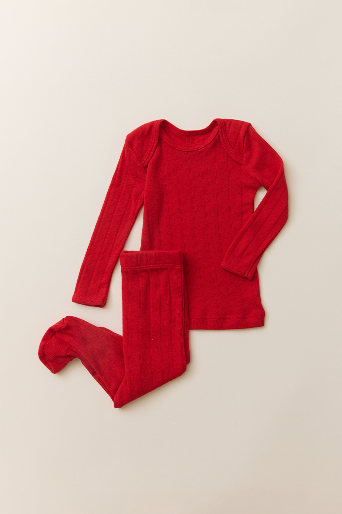 The Baby Sleep Set in red pointelle, featuring a long-sleeve top and matching footed leggings laid flat on a neutral background.