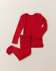 The Baby Sleep Set in red pointelle, featuring a long-sleeve top and matching footed leggings laid flat on a neutral background.