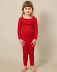 Young girl wearing a red pointelle outfit against a beige background