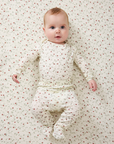 Baby in a strawberry outfit lying on a matching patterned blanket