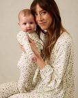 Woman and baby wearing matching pajamas against a plain background