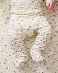 Baby in a strawberry outfit with red strawberries lying on a strawberry-patterned blanket
