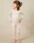 Young girl wearing a strawberry pajama set on a beige background