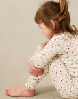 Child wearing a strawberry outfit sitting on a beige surface