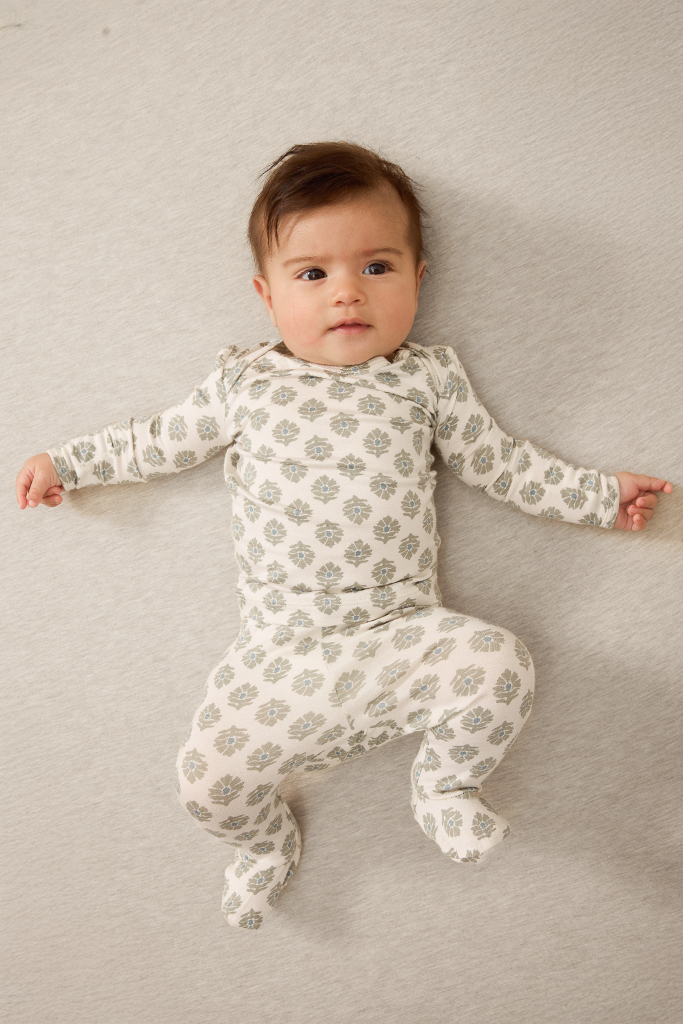 Baby wearing a patterned onesie lying on a neutral background