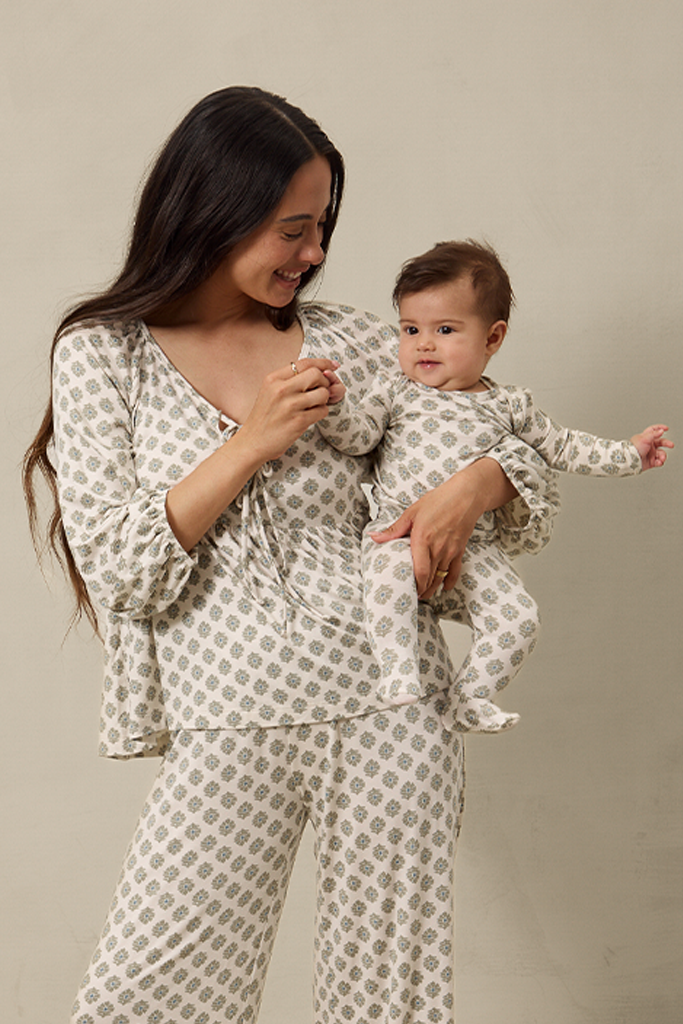 Woman and baby wearing matching patterned outfits against a neutral background