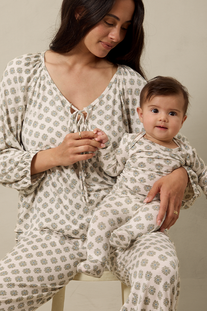 Woman and baby in matching patterned outfits sitting together.